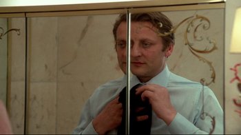 Movie still from “Sorcerer” (1977), directed by William Friedkin – A man is fixing his tie in the mirror; Close Up shot, Low angle