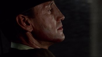 Movie still from “Sorcerer” (1977), directed by William Friedkin – An older man wearing a black hat looking to his left; Close Up shot, Low angle