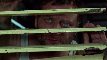 Movie still from “Sorcerer” (1977), directed by William Friedkin – A person looking through a window; Close Up shot, Low angle