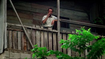 Movie still from “Sorcerer” (1977), directed by William Friedkin – A man standing on a balcony brushing his teeth; Medium shot, Low angle