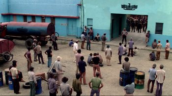 Movie still from “Sorcerer” (1977), directed by William Friedkin – A group of people standing around in a courtyard; Extreme Wide shot, High angle