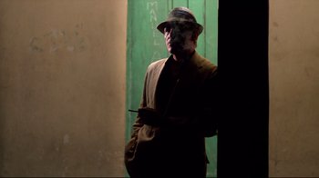 Movie still from “Sorcerer” (1977), directed by William Friedkin – A man with a hat and a cigarette in his mouth; Medium shot, Over the shoulder angle