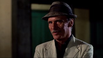 Movie still from “Sorcerer” (1977), directed by William Friedkin – A person wearing a suit and a hat; Close Up shot, Low angle