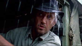 Movie still from “Sorcerer” (1977), directed by William Friedkin – A person wearing a hat in the rain; Close Up shot, Low angle
