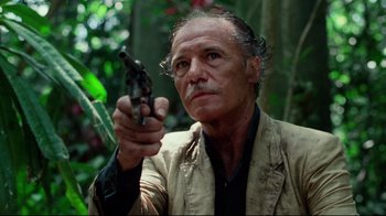 Movie still from “Sorcerer” (1977), directed by William Friedkin – An older man holding a gun in the woods; Close Up shot, Low angle