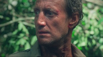 Movie still from “Sorcerer” (1977), directed by William Friedkin – A person with a scar on his face; Close Up shot, Over the shoulder angle