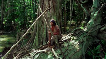 Movie still from “Sorcerer” (1977), directed by William Friedkin – A man sitting on top of a tree in the woods; Wide shot, High angle