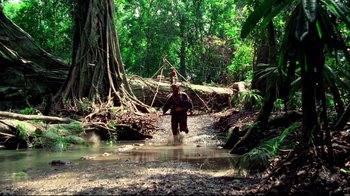 Movie still from “Sorcerer” (1977), directed by William Friedkin – A man is walking through a stream in the woods; Extreme Wide shot, Low angle
