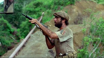 Movie still from “Sorcerer” (1977), directed by William Friedkin – A man holding a rifle on top of a hill; Medium shot, Low angle