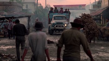 Movie still from “Sorcerer” (1977), directed by William Friedkin – A group of people riding in the back of a truck down a dirt road; Wide shot, Over the shoulder angle