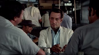 Movie still from “Sorcerer” (1977), directed by William Friedkin – A man sitting at a table with a cup of coffee in front of him; Medium shot, Over the shoulder angle