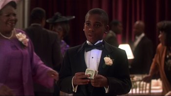 Movie still from “Soul Food” (1997), directed by George Tillman Jr. – A young man in a tuxedo holding a dollar bill in his hands; Medium shot, High angle