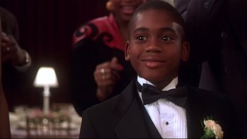 Movie still from “Soul Food” (1997), directed by George Tillman Jr. – A young boy in a tuxedo smiling for the camera; Close Up shot, High angle