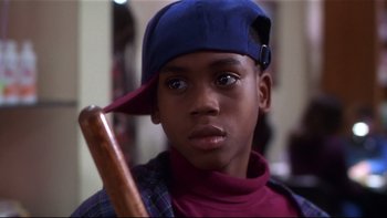 Movie still from “Soul Food” (1997), directed by George Tillman Jr. – A young boy wearing a baseball cap and holding a baseball bat; Close Up shot, Low angle