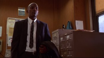 Movie still from “Soul Food” (1997), directed by George Tillman Jr. – A man in a suit and tie standing in front of some filing cabinets; Medium shot, Low angle