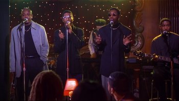Movie still from “Soul Food” (1997), directed by George Tillman Jr. – A couple of people that are singing on a stage; Medium shot, Low angle