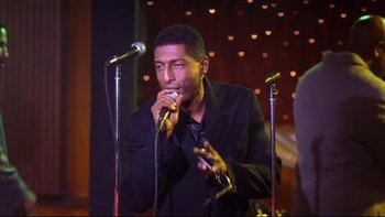 Movie still from “Soul Food” (1997), directed by George Tillman Jr. – A man in a black jacket is singing into a microphone; Close Up shot, Low angle