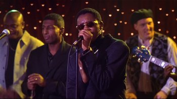 Movie still from “Soul Food” (1997), directed by George Tillman Jr. – A man singing into a microphone in front of a group of people; Medium shot, Low angle