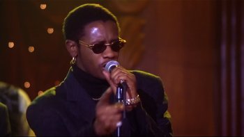Movie still from “Soul Food” (1997), directed by George Tillman Jr. – A man in a black jacket is holding a microphone; Close Up shot, Low angle