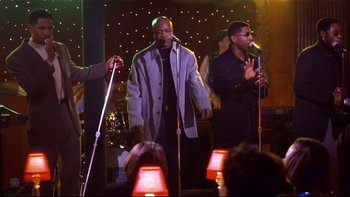Movie still from “Soul Food” (1997), directed by George Tillman Jr. – A group of men singing on a stage with microphones; Medium shot, Low angle