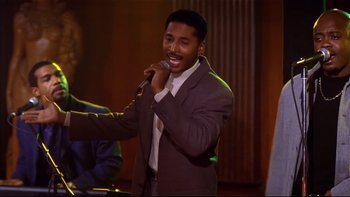 Movie still from “Soul Food” (1997), directed by George Tillman Jr. – A man in a brown suit is singing into a microphone; Medium shot, Low angle