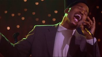 Movie still from “Soul Food” (1997), directed by George Tillman Jr. – A man in a suit and tie is singing into a microphone; Close Up shot, Low angle