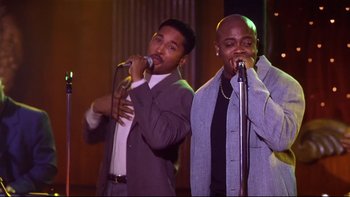 Movie still from “Soul Food” (1997), directed by George Tillman Jr. – A couple of men singing into microphones on a stage; Medium shot, Low angle