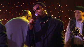 Movie still from “Soul Food” (1997), directed by George Tillman Jr. – A woman in a black jacket is singing into a microphone; Close Up shot, Low angle