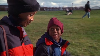 Movie still from “Soul Food” (1997), directed by George Tillman Jr. – Two young boys in a field talking to each other; Medium shot, Over the shoulder angle