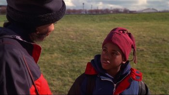 Movie still from “Soul Food” (1997), directed by George Tillman Jr. – A man and a boy are talking in a field; Close Up shot, Over the shoulder angle