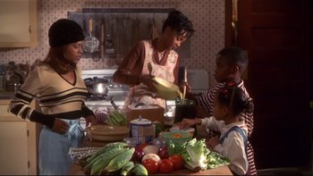 Movie still from “Soul Food” (1997), directed by George Tillman Jr. – A group of people gathered around a table with food; Medium shot, High angle