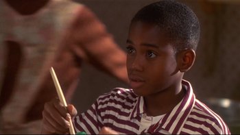Movie still from “Soul Food” (1997), directed by George Tillman Jr. – A young boy is playing with a drum stick; Close Up shot, High angle
