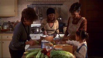 Movie still from “Soul Food” (1997), directed by George Tillman Jr. – A group of people standing around a table preparing food; Medium shot, High angle