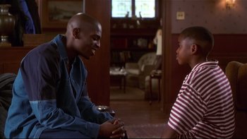 Movie still from “Soul Food” (1997), directed by George Tillman Jr. – A man and a woman sitting in a living room talking to each other; Medium shot, High angle