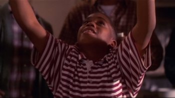Movie still from “Soul Food” (1997), directed by George Tillman Jr. – A young boy in striped shirt raising his hands; Close Up shot, Low angle