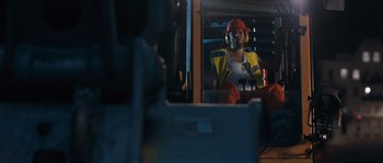 Movie still from “Sound of Noise” (2010), directed by Ola Simonsson – A man wearing a hard hat sitting in a vehicle; Medium shot, Low angle