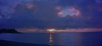 Movie still from “South Pacific” (1958), directed by Joshua Logan – The sun is setting over the ocean as the sun sets over the water; Extreme Wide shot, Low angle