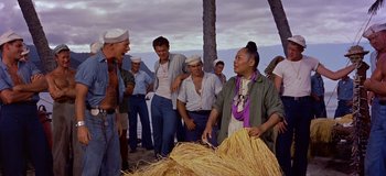 Movie still from “South Pacific” (1958), directed by Joshua Logan – A group of people standing around a pile of hay; Medium shot, Over the shoulder angle