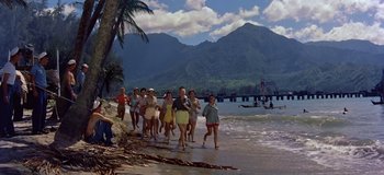 Movie still from “South Pacific” (1958), directed by Joshua Logan – A group of people walking along the beach; Extreme Wide shot, High angle