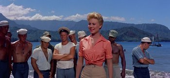 Movie still from “South Pacific” (1958), directed by Joshua Logan – A group of men standing next to each other on a beach; Medium shot, Low angle