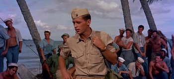 Movie still from “South Pacific” (1958), directed by Joshua Logan – A man in a military uniform is holding a bag; Medium shot, Low angle