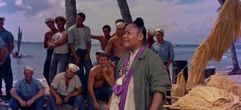 Movie still from “South Pacific” (1958), directed by Joshua Logan – A group of men sitting on the beach; Medium shot, Over the shoulder angle