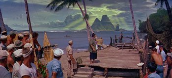 Movie still from “South Pacific” (1958), directed by Joshua Logan – A group of people standing on top of a beach; Extreme Wide shot, High angle