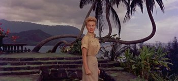 Movie still from “South Pacific” (1958), directed by Joshua Logan – A woman standing in front of a body of water and palm trees; Medium shot, Low angle