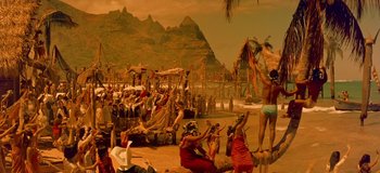 Movie still from “South Pacific” (1958), directed by Joshua Logan – A group of people standing on top of a sandy beach; Extreme Wide shot, High angle