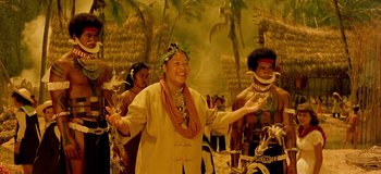 Movie still from “South Pacific” (1958), directed by Joshua Logan – A group of people standing in a room with palm trees; Medium shot, Over the shoulder angle