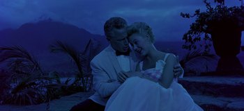 Movie still from “South Pacific” (1958), directed by Joshua Logan – A man and a woman in a white suit and pink checkered dress; Medium shot, Low angle