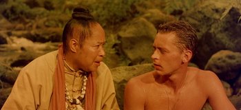 Movie still from “South Pacific” (1958), directed by Joshua Logan – A man sitting next to another man in front of some rocks; Close Up shot, Over the shoulder angle