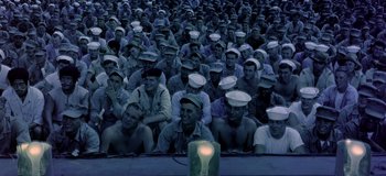 Movie still from “South Pacific” (1958), directed by Joshua Logan – A large group of sailors sitting in front of a light; Extreme Wide shot, High angle