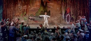 Movie still from “South Pacific” (1958), directed by Joshua Logan – A man in white shirt and white pants on stage; Wide shot, High angle